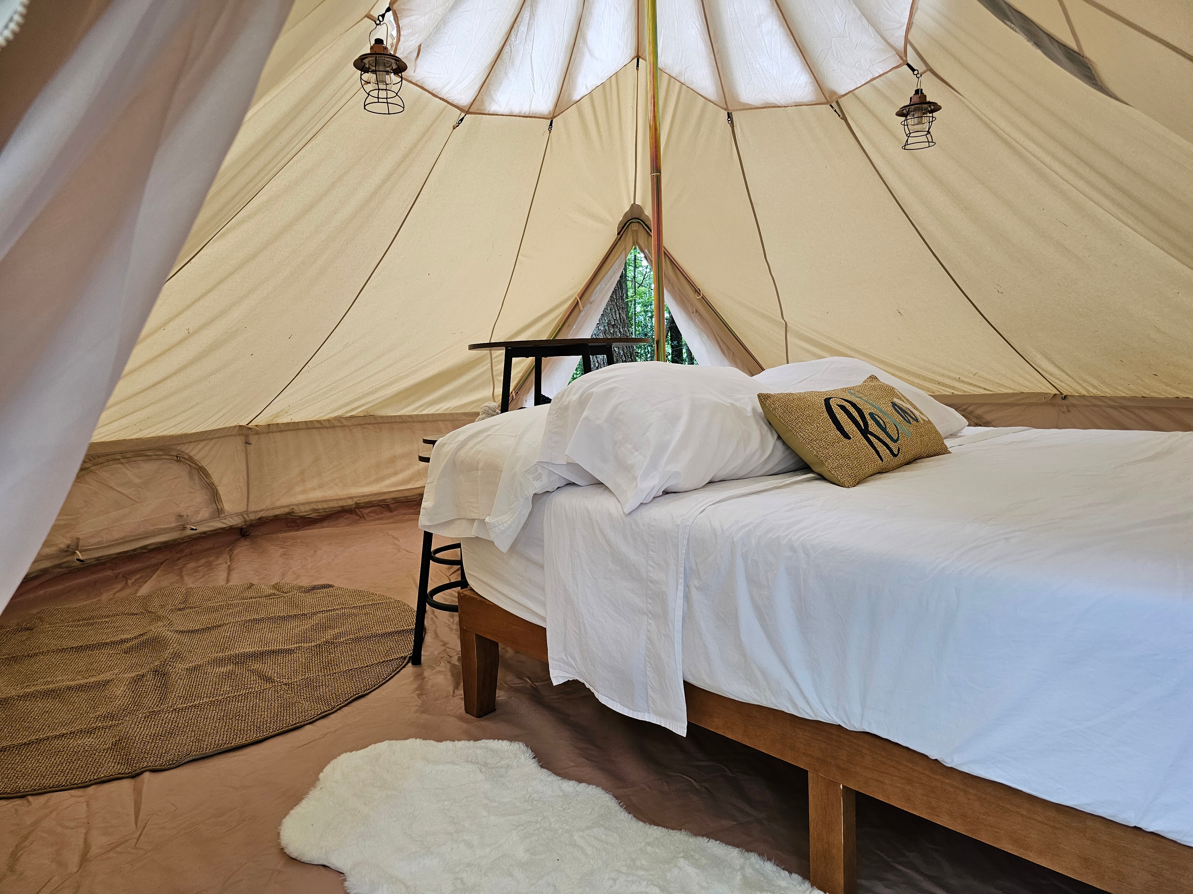 Glamping tent interior with bed and lanterns